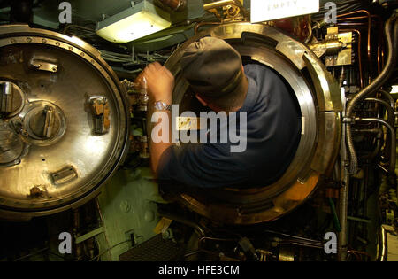 Ein Torpedoman an Bord des U-Bootes der Los Angeles-Klasse USS Portsmouth (SSN 707) steigt in eine Torpedoröhre ein, um eine Vorlageprüfung durchzuführen. Portsmouth wird nach Norfolk (Virginia) überführt und soll im September 2004 stillgelegt werden, um die Betriebsbereitschaft und die Sicherheitsmaßnahmen während des Transports zu gewährleisten. Stockfoto