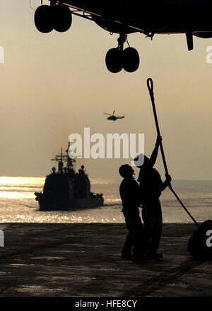 050115-N-2984R-019 Persischen Golf (14. Januar 2005) - Segler an Bord der USS Harry S. Truman (CVN-75) Haken ein Nachschub-Pendant zum Puma Helikopter während einer im Gange Nachschub mit dem Military Sealift Command (MSC) Bekämpfung Store Schiff USNS Saturn (T-AFS-9), während die Lenkflugkörper Kreuzer USS Monterey (CG-61) Manöver achtern des Trägers. Carrier Air Wing drei (CVW-3) ist ist an Bord der USS Harry S. Truman (CVN-75) begonnen und Luftnahunterstützung und Durchführung von Intelligenz, Überwachung und Aufklärungsmissionen über den Irak. Die Truman-Strike Group und CVW-3 sind auf eine regelmäßige Stockfoto