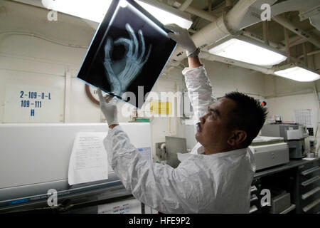 050211-N-1229B-034 Philippinensee (11. Februar 2005) - Hospital Corpsman 1. Klasse Jose Afable schaut ein Röntgenbild eines gebrochenen Fingers in der medizinischen Abteilung an Bord der Flugzeugträger der Nimitz-Klasse USS Abraham Lincoln (CVN-72). Lincoln und eingeschifften Carrier Air Wing Two (CVW-2) sind derzeit im Einsatz auf den westlichen Pazifischen Ozean. Foto: U.S. Navy des Fotografen Mate Airman Patrick M. Bonafede (freigegeben) US Navy 050211-N-1229B-034 Hospital Corpsman 1. Klasse Jose Afable schaut ein Röntgenbild eines gebrochenen Fingers in der medizinischen Abteilung an Bord der Flugzeugträger der Nimitz-Klasse USS Abraham Lincoln (CV Stockfoto