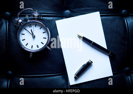 Nahaufnahme von stilvollen Stift mit weißem Papier und Wecker auf schwarzem Leder Stockfoto