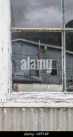 Kleinstadt Postamt Flagge spiegelt sich in einem alten Fenster eines Fabrikgebäudes. Stockfoto