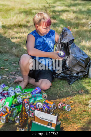 Ein Junge über zehn Jahre alte sammelt Dosen und Flaschen in schwarz meschotschek für das recycling in Vermont, USA. Stockfoto