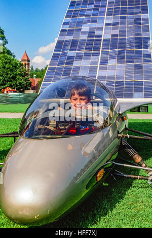 Ein kleiner Junge sitzt im Cockpit eines solar betriebenen Autos auf dem Display bei einer Show von Solartechnik. Stockfoto