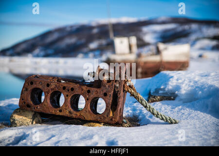 Alten Rastyboat Motor auf dem Schnee am See in der Nähe das Fischerboot im winter Stockfoto