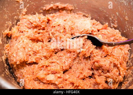 Schale mit Boden Schweine- und Rindfleisch Mischung mit Gewürzen und Zwiebeln für die Herstellung von Frikadellen. Löffel in der Mischung. Stockfoto