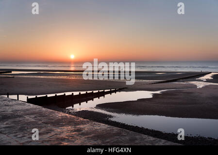 Winter-Sonnenuntergang über dem Badeort Cleveleys, Lancashire, mit weit entfernten Horserider am Strand Stockfoto