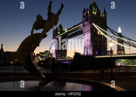 Tower Bridge bei Nacht von dem Mädchen mit einem Delfin-Statue gesehen. Stockfoto