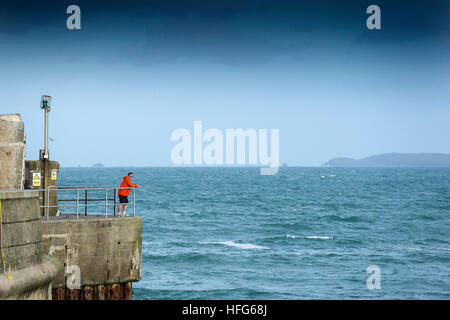 Ein Mann steht am Kai mit Blick auf den Eingang zum Hafen von Newquay in Cornwall, England, UK. Stockfoto