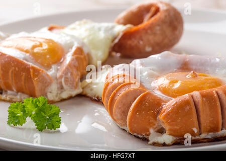 Gebratene Würstchen und Eiern auf weißen Teller Stockfoto