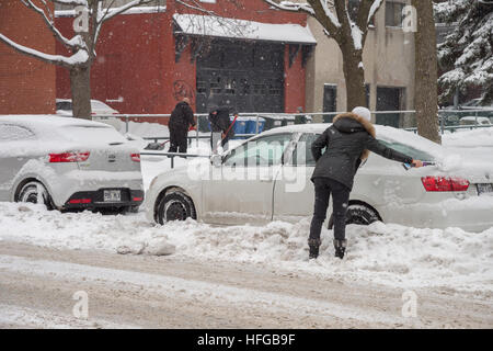 Montreal, CA - 12. Dezember 2016: Frau reinigen ihr Auto aus dem Schnee bei Schneefall im Winter. Stockfoto