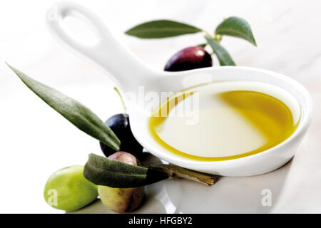 Porzellanlöffel mit Olivenöl und Oliven Stockfoto