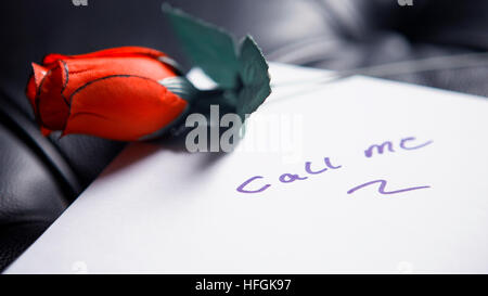 Rufen Sie die Worte auf Papier geschrieben, mit roten Rose auf schwarzem Leder Stockfoto