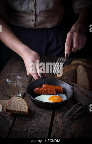 Frau hält eine Pfanne mit Spiegelei und Würstchen. Selektiven Fokus Stockfoto