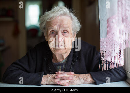 Ältere Frau Porträt, sitzen im Haus. Stockfoto