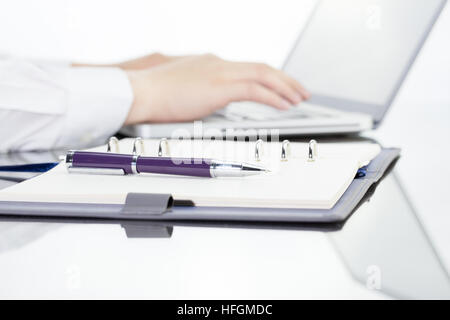 Geschäftsmann schreiben Sie eine kurze Notiz auf geöffneten Notizbuch mit Stift und Gläser. Stockfoto