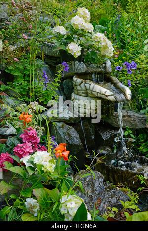 Kleine dekorative Brunnen im Garten mit Blumen geschmückt Stockfoto