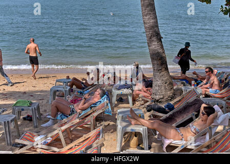 Westliche Touristen an einem tropischen Strand Sonnenbaden. Pattaya Thailand S. E. Asien Stockfoto