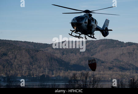 Kochel Am See, Deutschland. 2. Januar 2017. Ein Hubschrauber fliegen über See Kochel in Kochel Am See, Deutschland, 2. Januar 2017. Ein Bergsteiger verursachte ein Brand auf dem Jochberg-Berg. Etwa hundert Hektar Wald und Wiesen waren in Brand und die Feuerwehr konnte noch ein paar Tage um das Feuer zu löschen nach der Kreisverwaltung. Foto: Sven Hoppe/Dpa/Alamy Live News Stockfoto