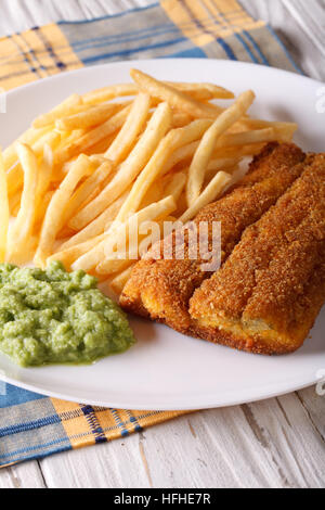 Englisch Essen: gebratene Fischfilets und Chips und Erbsen Püree Nahaufnahme auf einer Platte. Vertikal Stockfoto