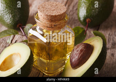 frische Avocado-Öl in eine Flasche aus Glas auf einem Holztisch Makro, horizontale Stockfoto