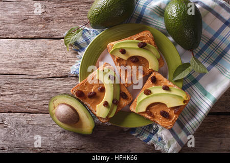 Hausgemachte Sandwiches mit Erdnussbutter, Rosinen und Avocado auf einem Teller. horizontale Ansicht von oben Stockfoto