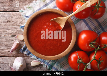 Tomatensauce mit Knoblauch und Basilikum in einer Holzschale Nahaufnahme. horizontale Ansicht von oben Stockfoto