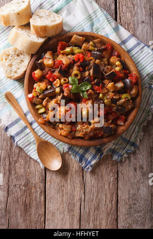 Italienische Caponata mit Auberginen in einer hölzernen Platte. vertikale Ansicht von oben Stockfoto