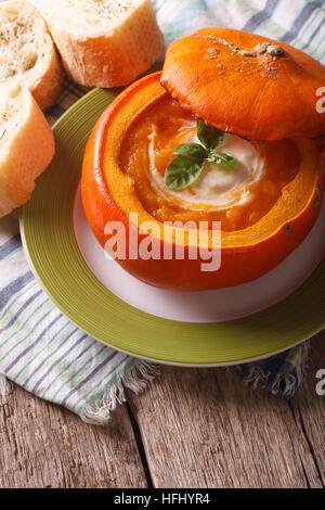 Diätetische Püree-Suppe mit saurer Sahne und Basilikum in einen Kürbis hautnah. Vertikal Stockfoto