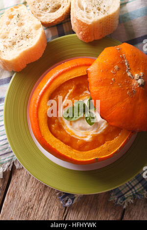 Kürbissuppe mit saurer Sahne und Basilikum Nahaufnahme gebacken. vertikale Ansicht von oben Stockfoto