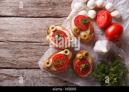 Crostini mit Tomaten, Oliven und Käse auf dem Tisch. horizontale Ansicht aus Stockfoto