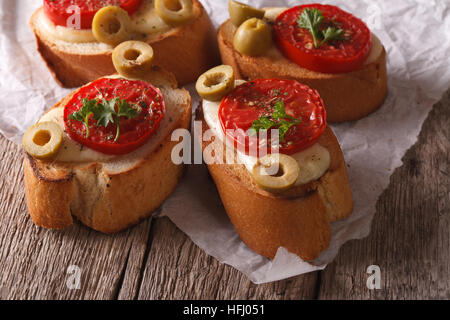 Italienische Bruschetta mit gebackenen Tomaten, Oliven und Mozzarella Käse close-up auf dem Tisch. horizontale Stockfoto