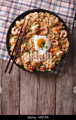 Asiatische Reispfanne Nasi Goreng mit Huhn, Garnelen, Ei und Gemüse vertikale Ansicht von oben Stockfoto