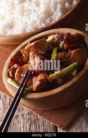 Kung Pao Hühnerfleisch in einer Schüssel hautnah und Reis auf dem Tisch. Vertikal Stockfoto