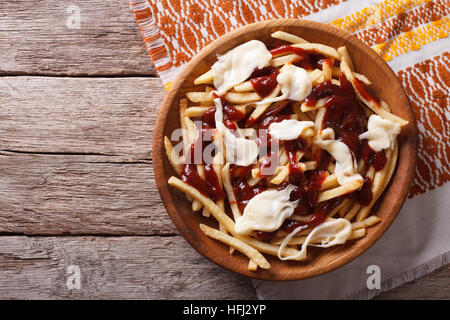 Kanadische Küche: Poutine mit Sauce und Käse auf dem Tisch. horizontale Ansicht von oben Stockfoto