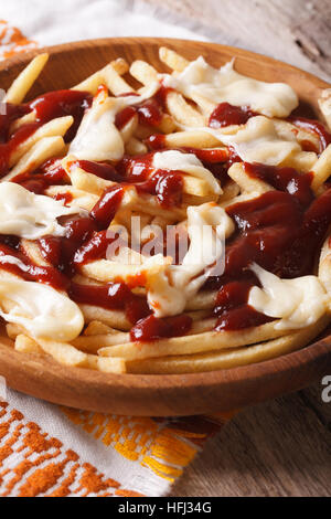 Traditionelle kanadische Fastfood Poutine mit Sauce und Käse Nahaufnahme auf dem Tisch. Vertikal Stockfoto