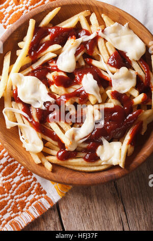 Kanadische Snack: Poutine mit Sauce und Käse Nahaufnahme auf dem Tisch. vertikale Ansicht von oben Stockfoto