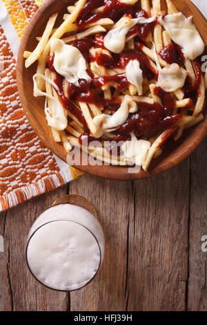 Poutine und Bier auf den Tisch-Nahaufnahme. vertikale Ansicht von oben Stockfoto