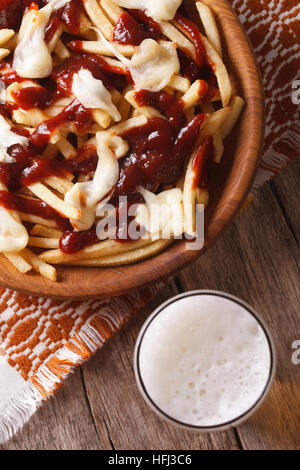 Kanadische Küche: Poutine und Bier auf den Tisch-Nahaufnahme. vertikale Ansicht von oben Stockfoto