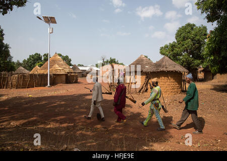 Gbderedou Baranama, Guinea, 2. Mai 2015; eine Gruppe von Jägern aus dem Dorf mit ihren Gewehren vorbei neu Installiert solarbetriebene Straßenbeleuchtungen. Stockfoto