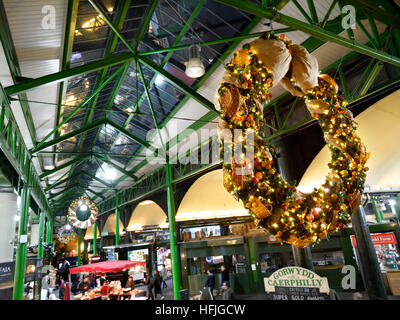 Erhöhte Sicht der späten Nacht Käse Marktstände und Verkostung Proben, Produkte unter dem Motto Weihnachten Kranz hängen im Vordergrund Borough Markt Southwark London SE1 Stockfoto