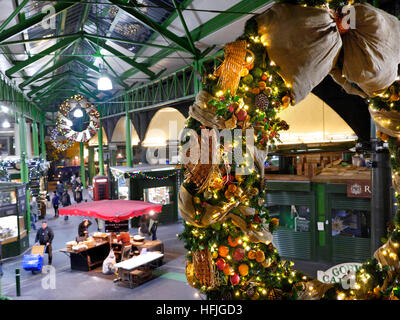 Erhöhte Sicht der späten Nacht Käse Marktstände und Verkostung Proben, Produkte unter dem Motto Weihnachten Kranz hängen im Vordergrund Borough Markt Southwark London SE1 Stockfoto