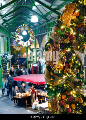 BOROUGH MARKET WEIHNACHTEN erhöhten Blick auf den späten Abend Käse Marktstände und Verkostung Proben, mit produzieren themenbezogene Weihnachten Kranz hängen in den Vordergrund Borough Market Southwark London SE1 Stockfoto