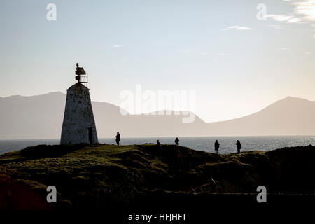 Besucher genießen den Blick auf Llanddwyn Island mit Twr Bach Leuchtturm Silhouette gegen die Llyn Halbinsel Mountain range Stockfoto