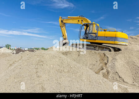 Gelbe Bagger macht Flor des Bodens durch Hochziehen Boden auf Heap auf Baustelle, Projekt im Gange. Stockfoto