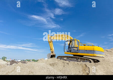 Gelbe Bagger macht Flor des Bodens durch Hochziehen Boden auf Heap auf Baustelle, Projekt im Gange. Stockfoto