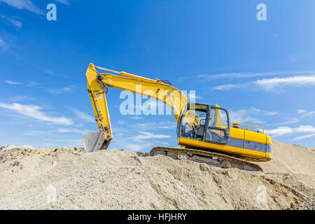 Gelbe Bagger macht Flor des Bodens durch Hochziehen Boden auf Heap auf Baustelle, Projekt im Gange. Stockfoto