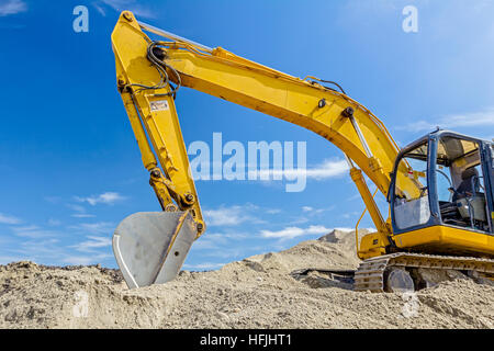 Gelbe Bagger macht Flor des Bodens durch Hochziehen Boden auf Heap auf Baustelle, Projekt im Gange. Stockfoto