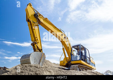 Gelbe Bagger macht Flor des Bodens durch Hochziehen Boden auf Heap auf Baustelle, Projekt im Gange. Stockfoto