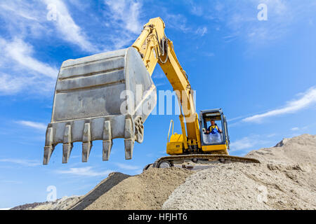 Gelbe Bagger macht Flor des Bodens durch Hochziehen Boden auf Heap auf Baustelle, Projekt im Gange. Stockfoto