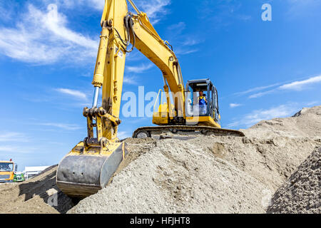 Gelbe Bagger macht Flor des Bodens durch Hochziehen Boden auf Heap auf Baustelle, Projekt im Gange. Stockfoto